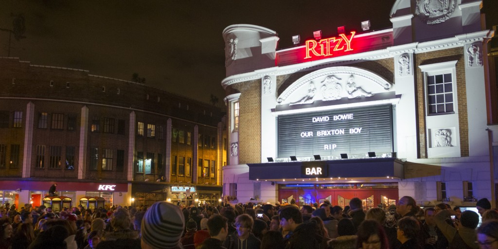 LONDON, ENGLAND - JANUARY 11: Members of the public gather outside the Ritzy Cinema in Brixton to pay tribute to David Bowie on January 11, 2016 in London, England. British music and fashion icon David Bowie died earlier today at the age of 69 after a battle with cancer. on January 11, 2016 in London, England. (Photo by John Phillips/Getty Images)